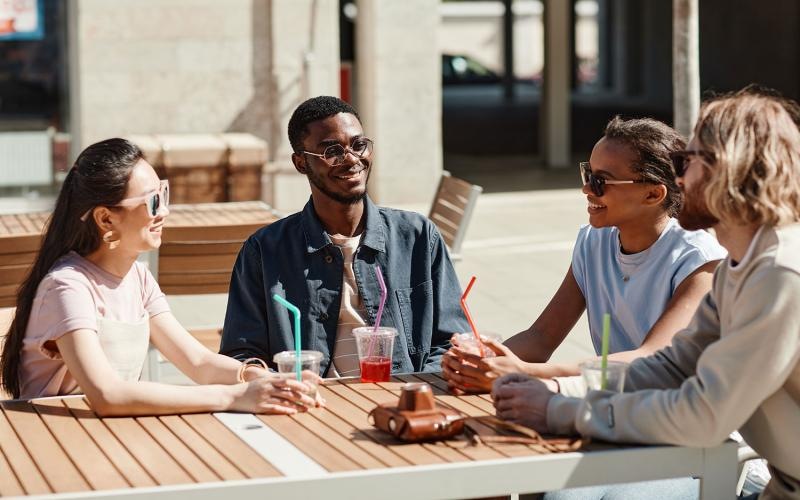 a group of people sitting at an outdoor table with drinks