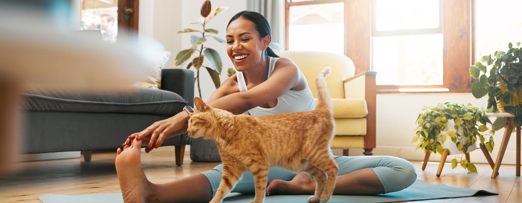 woman stretches on living room floor next to her cat